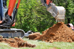 backhoe-digging-dirt-in-a-lawn-to-install-electric-2023-11-27-04-52-36-utc